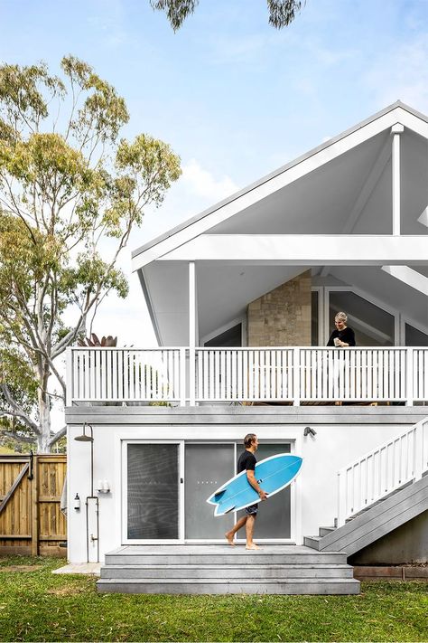 Two storey white beach house exterior with pitched roof, stone feature wall and outdoor shower. 2 Storey Beach House, White Beach House Exterior, Alfresco Ideas, Outdoor Shower Ideas, White Beach House, Engineered Timber Flooring, Outdoor Showers, Beach House Exterior, Mcm House