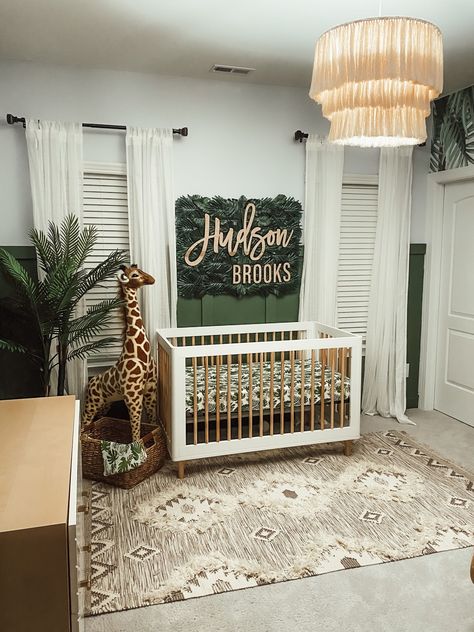 We fell in love with the wall mural, and the room fell in place around it. I knew if we did a jungle theme the traditional rocker needed to be replace with a swing. The crib bring and dresser put a modern twist on the room while also pulling a natural element with the natural color incorporated. A few elements in the room were DIY including the ceiling light, the elephant bookcase, and the palm leaf name wall hanging. Jungle Nursery Boy, Jungle Baby Room, Jungle Themed Nursery, Jungle Theme Nursery, Boy Nursery Themes, Jungle Nursery Decor, Safari Theme Nursery, Wallpaper Nursery, Baby Boy Room Decor