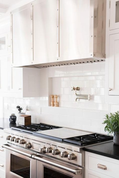 Beautiful white and black kitchen features a stainless steel dual range positioned between white drawers accented with polished nickel cup pulls and a black quartz straight edge countertop contrasting white subway backsplash tiles framing a tiled niche fitted with a polished nickel swing arm pot filler mounted beneath a stainless steel vent hood. Stove Pot Filler, Kitchen Niche, Trendy Kitchen Backsplash, Recessed Shelves, Ideas For Kitchen, Pot Filler, Kitchen Stove, Transitional Kitchen, Chic Kitchen