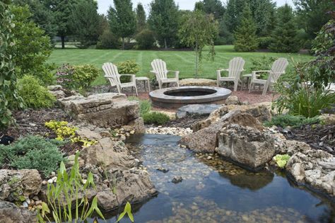 This water feature streams its way toward a fire pit with seating Landscaping With Fire Pit, Fire Pit With Seating, Fire Pit And Pond, Patio Water Feature, Large Water Features, Outside Fire Pits, Backyard Fire Pit, Fire Pit Landscaping, Backyard Water Feature