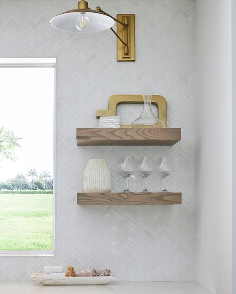 A brass swing arm sconce is mounted to white herringbone backsplash tiles over stacked chunky oak floating shelves. White Herringbone Wall, Herringbone Wall Tile, White Herringbone Backsplash, Akdo Tile, Marble Herringbone Tile, Floating Kitchen Shelves, Floating Kitchen, Herringbone Tile Backsplash, Styled Kitchen