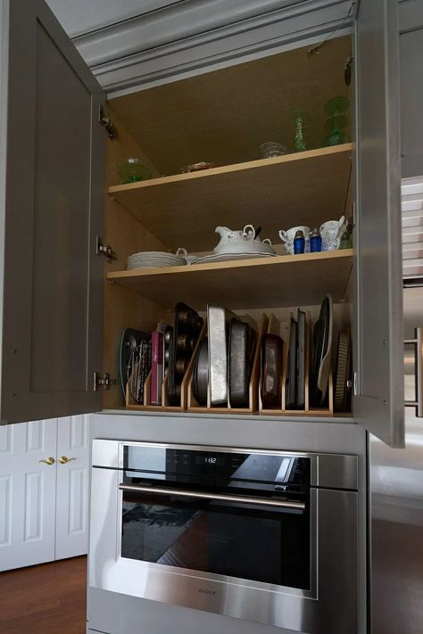 A tray divider rack organizes muffin tins, pans, and other bakeware inside the cabinet above a wall oven or toaster oven. Waterfall Countertop, Bakeware Storage, Cabinet Door Style, Transitional Kitchen Design, Upper Kitchen Cabinets, Pan Storage, Frameless Cabinets, Pantry Wall, Spice Drawer