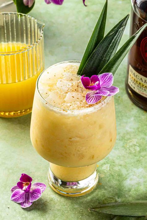 Made with dark rum, cream of coconut, and a splash of orange and pineapple juice, this painkiller cocktail is the perfect way to unwind with a tropical drink. Garnish with fresh nutmeg and a pineapple slice for that extra touch of Caribbean flavor. Cheers to sunshine and good vibes. Coconut Rum Cocktails, Painkiller Drink, Pirate Drinks, Tropical Cocktail Recipes, Drink Garnish, Banana Cocktails, Painkiller Cocktail, Cream Of Coconut, Rum Cream