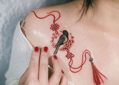 Korean magpie with red strings and cherry blossoms, done in New York in January.  #tattooistsion #tattoo #collarbone Bird Shoulder Tattoos, Korean Tattoo, Charm Tattoo, Korean Tattoo Artist, Create A Tattoo, Petit Tattoo, Korean Tattoos, Intricate Tattoo, Delicate Tattoo