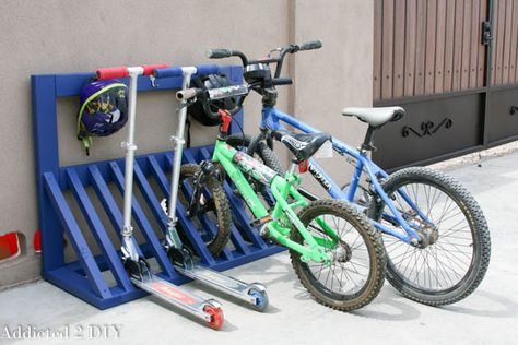 Don't leave bicycles and scooters toppled over in a corner--use a rack to safely park them. Diy Bike And Scooter Rack, Scooter Rack, Scooter Parking, Kids Bike Storage, Diy Bicycle, Diy Bike Rack, Helmet Storage, Garage Organization Tips, Bicycle Stand