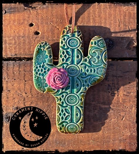 Handmade Ceramic Ornament by Susan Boyles Handmade, ceramic clay cactus ornament with a lace pattern and a pink rose! These ornaments make wonderful gifts throughout the year! Glazed and fired in a beautiful turquoise color with hints of rustic green around the edges. Ornament measures 4" tall x 3" wide. Ornament comes with an attached leather cord for hanging. Because every ornament is handmade; shape, color, flower placement pattern and size will vary slightly. All orders are shipped via USPS First Class Mail with tracking info. Please allow up to 2 weeks for delivery of your order. Desert Ornaments, Pottery Cactus, Clay Cactus, Handbuilt Pottery, Arizona Decor, Desert Clay, Cactus Ceramic, Pottery Ornaments, Marble Falls