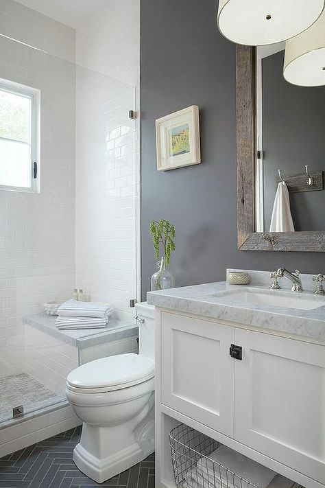 Gray and white bathroom features a white washstand fitted with a shelf holding a metal bin and a carrera marble countertop holding a sink with a polished nickel cross handle faucet beneath a reclaimed wood beveled vanity mirror mounted on a gray wall lit by a white drum pendant. Makeover Kamar Mandi, Grey And White Bathroom, Tub Remodel, Bathroom Tub, Bathroom Remodel Designs, White Vanity, Decor Baie, Basement Bathroom, Bathroom Redo