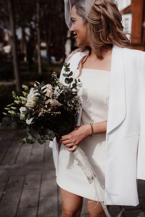 Bride in White Blazer & Short Wedding Dress and Birdcage Veil with White Flower and Foliage Bouquet City Hall Wedding Dress, Foliage Bouquet, Town Hall Wedding, Short Bridal Dress, Boda Ideas, Wedding Carriage, Civil Wedding Dresses, Beige Wedding, Bridal Jacket