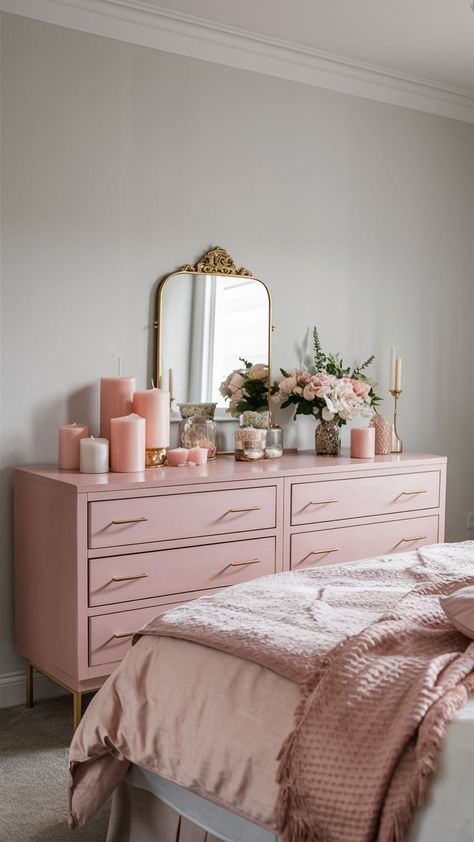 A soft blush pink dresser with gold handles, set against a light gray wall, adorned with delicate decor items like a gold-framed mirror, candles, and fresh flowers. Blush Pink Dresser, Bedroom With Dresser, Dusty Pink Bedroom, Blush Pink Bedroom, Pink Dresser, Pink Bedrooms, Bedroom Dresser, Dresser Decor