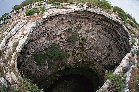 Texas, US: The Devil's Sinkhole with people gathered to view bats Sinkhole Forest, Alien Jungle, Nature Shapes, Camping In Texas, Camping Destinations, Weather Seasons, Hades And Persephone, Texas Travel, Natural Phenomena