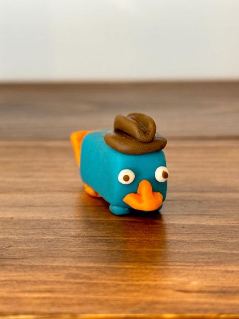 🦆 Meet Perry the Platypus, your favorite secret agent in an adorable handmade polymer clay figurine! Ready to join your collection! Polymer Clay Ideas Animals, Small Clay Designs, Clay Crafts Animals Easy, Clay Action Figures, Ratatouille Clay, Cute Polymer Clay Figures, Mini Clay Ideas Easy Simple, Clay Rick And Morty, Little Clay Figures Easy