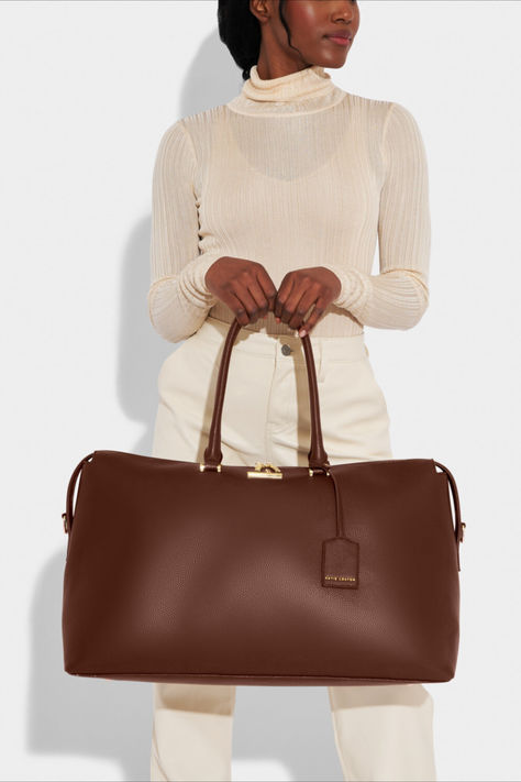 Discover the carryall you'll want to carry everywhere. Exploring different silhouettes whilst taking notes from our bestselling weekend bags, Katie Loxton designed the chocolate Kensington bag with a softly structured silhouette and neatly tapered sides. It comes with a top carry handle, detachable over the shoulder strap and a gorgeous complementing luggage tag, perfect for personalising. Colour: Chocolate Material: Vegan Leather (100% PU) Height: 30cm Width: 53cm Weekend Bags For Women, Bride To Be Gifts, Weekend Bags, The Adventure Begins, Head Off, Adventure Begins, Luxury Jewellery, Weekend Bag, Taking Notes