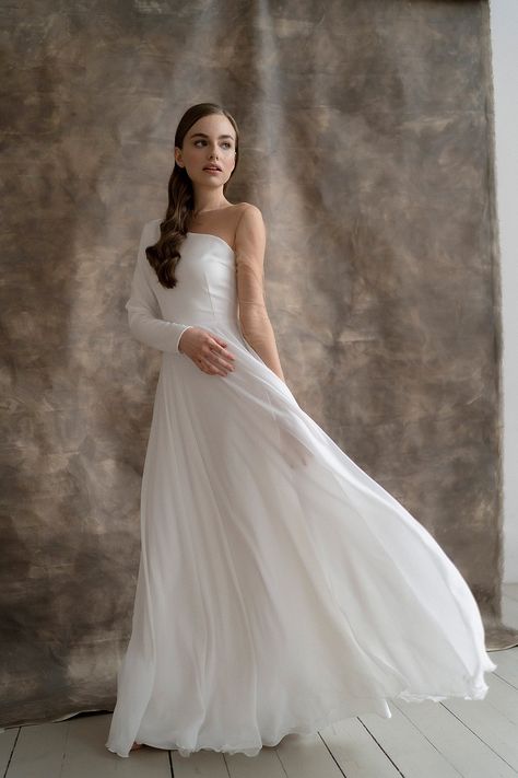 The Luna wedding dress is made of chiffon and satin. One shoulder and the sleeve are completely covered with a body mesh – this gives a very beautiful effect of a “bare” hand. #a line dress #bohemian dress #boho dress #chiffon wedding #elegant dress #ivory wedding dress #long sleeve dress #one shoulder dress #simple dress #wedding dress Simple Dress Wedding, Wedding Elegant Dress, Chiffon Wedding Gowns, Minimalist Wedding Dress, Grey Wedding Dress, Boho Gown, Modest Wedding Gowns, Handmade Wedding Dresses, Crepe Wedding Dress