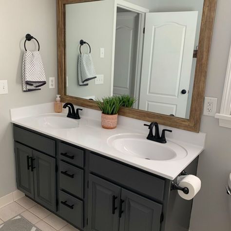 My builder grade Master Bathroom vanity was bad. Really bad. After two years I finally decided to do something about it and got to work. Here’s a before photo of the bathroom.    Break Out the Spray Cans    I used a can of Rustoleum Matte Black spray paint I had in the basement on the light fixture for a quick, easy and free light refresh! Cover Everything!    For the countertop I purchased a $4.00 can of Rustoleum Appliance Epoxy spray paint from Walmart. I heard it produced lots of o… Gray Bathroom Vanity Paint Colors, Black Chalk Paint Bathroom Vanity, Redone Bathroom Vanity, Updated Builder Grade Bathroom, Black Vanity White Counter, Dark Stain Bathroom Vanity, Black Painted Vanity Bathroom, Best Black Paint For Bathroom Vanity, Bathroom Remodel Black Vanity