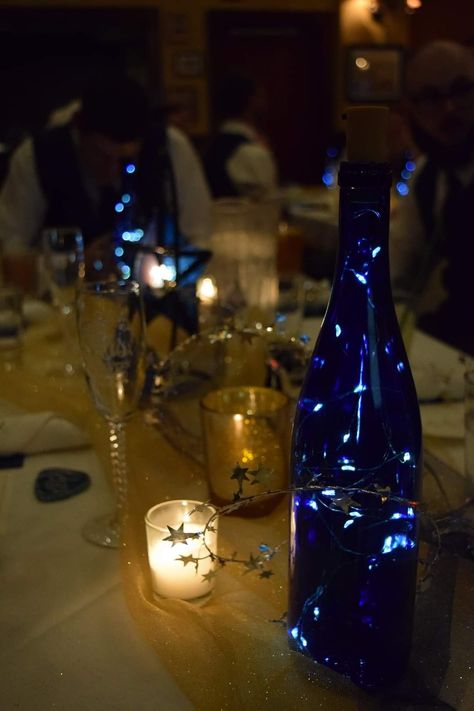 Blue Bottles With Fairy Lights, Midnight Theme Decorations, Midnight Themed Wedding, Wedding Venue Under The Stars, Night Under The Stars Theme Quince, Under The Stars Decorations Table Settings, Blue Wine Bottle Centerpieces, Midnight Blue And Black Wedding, Midnight Blue Wedding Decor