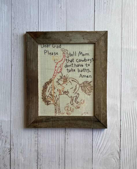 Dear God framed print is framed with barn wood. The picture is printed on fabric to look like it is stitched. The frame measures 14 1/2" x 12 1/2". The print is 8x10. Western Colonial Home, Vintage Cowboy Bathroom, Cowboy Nursery Art, Western Above Bed Decor, Western Inspired Home Decor, Cowboy Theme Room, Modern Cowboy Nursery, Cowboy Nursery Ideas, Cowboy Hat Wall Decor