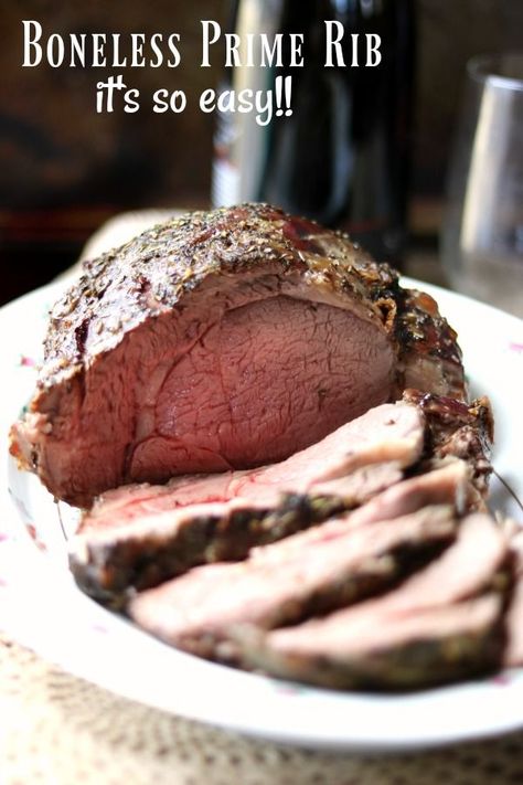 a boneless prime rib roast sliced on a white platter. A bottle of wine is in the background Slow Cooker Prime Rib, Boneless Prime Rib, Boneless Prime Rib Roast, Prime Rib Roast Recipe, Cooking Prime Rib, Rib Roast Recipe, Prime Rib Recipe, Prime Rib Roast, Rib Roast