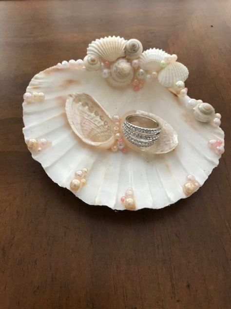 "Photos show previously created items.  I will create a custom ring holder for you using your wedding colors and whatever shells you like. Seashell ring holder perfect for beach wedding, tropical wedding or destination wedding. A beautiful white scallop shell can be painted gold or silver on the bottom side.  The ring bearer shell is decorated with seashells, starfish, coral or pearls. Each one of my items are designed one by one and are completely made with my own hands.  Seashell measures approximately 3.5\" in diameter. Current production time is about 5 - 10 days before shipping. Please let me know if you need it sooner so I may work with you.  If you are looking for a coordinating flower girl basket, chair sashes, or any other shell wedding accessories, please feel free to message me. Shell Ring Bearer, Decorated Shells, Shell Ring Holder, Painting Shells, Shell Gifts, Scallop Shell Craft, Beach Wedding Tropical, Seashell Art Diy, Sea Things