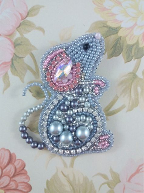 This cute Mouse brooch is full of life and sparkle. Made up with rhinestone chain, pearl beads and seed beads in shades of pink and grey.                                                                                                                     Measuring 7cms ( 2 3/4 inches ) in height and approximately 5cms ( 2 inches ) across taking in the tail. Backed with a pale cream ultra suede. A lovely addition to a Winter wardrobe or a beautiful gift. The original design is by Kseniia. Beaded Mouse, Diy Baubles, Sequin Crafts, Vintage Jewelry Ideas, Bead Crafts Diy, Creating Artwork, Vintage Jewelry Art, Rhinestone Chain, Cute Mouse