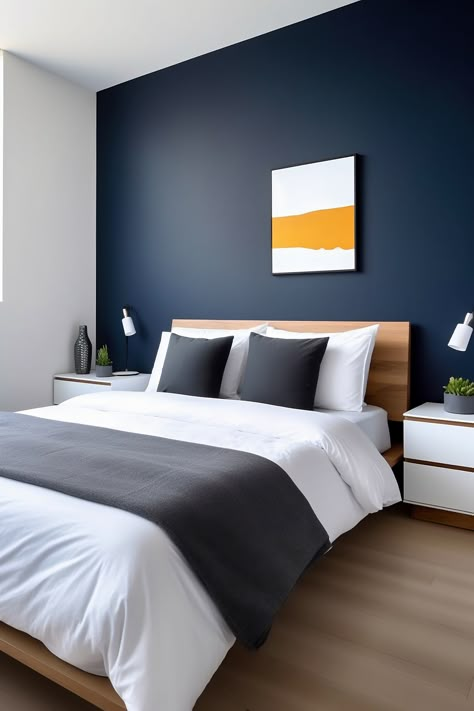 Photographed from an angle that captures the entire queen-size bed and most of the room, this modern bedroom features a midnight blue accent wall. Minimalist floating nightstands, a simple pendant light, and a white duvet cover complete the look. Midnight Blue Bedroom, Simplistic Bedroom, Blue Bedroom Walls, Mens Bedroom Decor, Blue Bedroom Design, Room Color Combination, Feature Wall Bedroom, Blue Accent Walls, Bedroom Color Combination