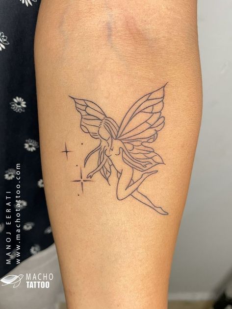 A photo of a tattoo on someone’s arm. The tattoo is of a fairy with wings and a dress. The tattoo is done in black ink and is in an outline style. The tattoo is located on the upper arm near the shoulder. The background is a black and white floral pattern. There is a watermark on the image that reads “MACHO TATTOO www.machotattoo.com”. The tattoo was done by Macho Tattoo, a professional tattoo studio in Hyderabad that offers a wide range of services and styles. Geometric Lion Tattoo, Tattoo Black And White, Black And White Outline, Lipstick Tattoos, Tiny Wrist Tattoos, Becoming A Tattoo Artist, Fairy Tattoo Designs, Moon Tattoo Designs, Small Pretty Tattoos