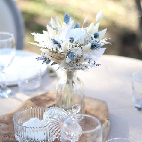 The soft and natural colors of ivory and dusty blue of this dried and preserved flowers composition invite you to dream and travel. Find the boho and friendly atmosphere of holidays by the sea with this centerpiece whose color evokes the twilight hour when the horizon mingles with the ocean. Bouquet hand made with preserved hydrangea and eucalyptus; Dried broom, oats, tatarica, hill flowers, phallaris and lagurus. These durable natural flowers will allow you to prepare your decoration in advance Blue Flower Centerpieces, Blue Wedding Centerpieces, Blue Centerpieces, Seaside Theme, Blue Themed Wedding, Dusty Blue Weddings, Preserved Flowers, Small Bouquet, Deco Wedding