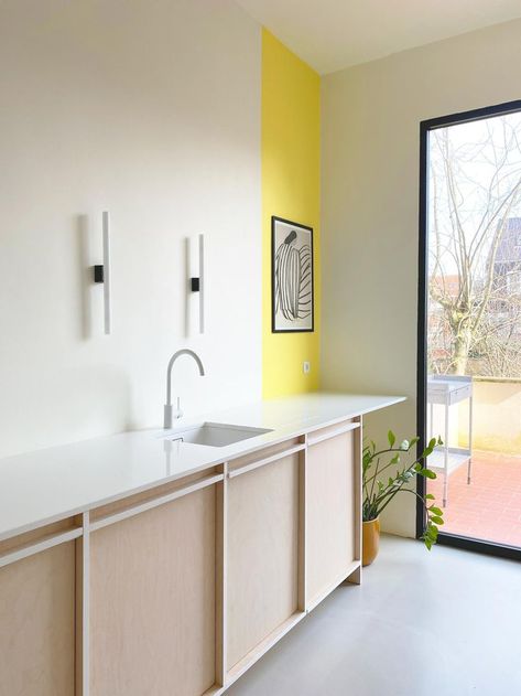 The kitchen design for Saartje and Sean starts from a rigid grid in birch veneer finished with white edges. The wood is combined with other sober materials, such as carrara marble, white composite and white lined fiber cement board. By creating a calm canvas there was still room left to work with colourful accents. Picture by Brent Pauwels. Wall Colour Ideas, Fiber Cement Board, Lamp Inspiration, Cement Board, Bright Kitchen, Compact House, Birch Veneer, Wall Colour, Fiber Cement