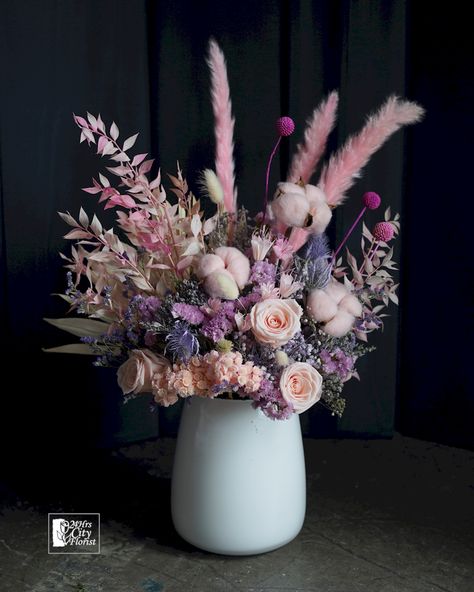 An endearing mix of dried and preserved flower arrangement of craspedia, statice, rice flower, pampas, cotton, pink ruscus, baby’s breath, rose, hydrangea and eryngium. Dried Pink Flower Arrangements, Pink Dried Flower Arrangement, Statice Flower Arrangement, Cotton Flower Arrangements, Preserved Flower Arrangement, Preserved Flower Bouquet, White Flower Centerpieces, Pine Cone Flower Wreath, Dried Arrangements