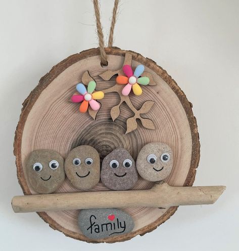 Add a touch of rustic charm to your home with this unique and cosy handmade log slice wall decor piece, featuring a beautiful and heart-warming family illustration made from pebble stone people with googly eyes.  The log slice is made from natural wood, and the small pebbles that adorn the piece complement its natural and earthy design. Designed for hanging, this log slice decor piece is perfect for display on any wall in your home, adding warmth and character to any room. It's also a wonderful gift idea for any occasion, especially for those who appreciate handmade and nature-inspired items. This piece is carefully crafted and includes a piece of driftwood and with the natural wood that make it truly one-of-a-kind. The googly eyes on the pebble stone people add a playful touch to the piec Driftwood Hanging, Wooden Log Slices, Family Pebble Art, Earthy Design, Log Slice, Log Slices, Wooden Log, Pebble Stone, Googly Eyes