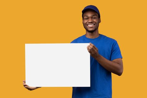 Shipment Service Promotion. Portrait of smiling bearded black delivery man in blue uniform holding and showing square empty blank board with template isolated on orange studio background Thumbnail Poses, Product Poster, Product Background, Blue Uniform, Advertising Board, Bible Characters, Logo Wall, Couple Selfies, Pose References