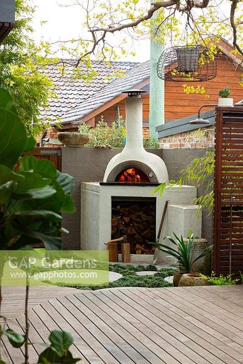 A bespoke cement rendered pizza oven in the back corner of a backyard showing a slat hardwood timber screen and a timber deck. Timber Screen, Italian Courtyard, Garden Pizza, Backyard Pizza Oven, Desert Backyard, Sunken Fire Pits, Brick Bbq, Brick Pizza Oven, Outdoor Oven