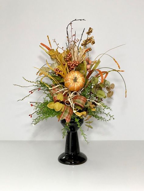 Fall Floral Centerpiece   �    Welcome! Check out this colorful, Fall floral arrangement centerpiece made with Autumn earthtone colors. This brown ceramic candlestick has pumpkin, berries, thistle, pinecone, Autumn leaves, greenery & accent picks with a touch of raffia. Highlighted with a plaid ribbon bow.      This would make a perfect centerpiece for your Fall, Autumn, Halloween or Thanksgiving table. Really would add a splash of color to your home decorations! Would make a great gift for someo