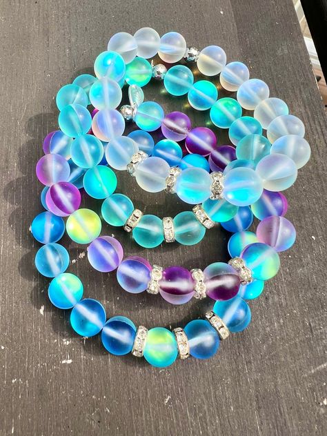 These are such beauties!! Perfect for your summer stacks! Mermaid glass beads are all the rage right now too! Because the beads are holographic, they pick up so many colors! Can be worn alone or added to a stack! Made with mermaid glass beads, silver crystal rondelle accents. Choose from four colors: Blue Aqua Dark Blue Purple White 10mm Mermaid Glass Beads 8mm Silver Plated Crystal Rondelles Measures at approx 7.5 inches. Due to the larger bead size, this bracelet will fit a little small. If yo Chunky Mermaid, Dark Blue Purple, Mermaid Glass, Halloween Bracelet, Bracelets Silver, Bead Charms Diy, Beads Bracelet Design, Beaded Jewelry Designs, Summer Bracelets