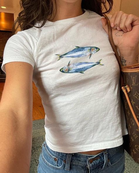 Dive into the nostalgic vibes of the 90s and Y2K era with our "Sardines Baby Tee Coquette Shirt." This slim-fit, mid-length baby tee is designed to hug your curves, offering a flattering silhouette that's perfect for the "Oceancore" aesthetic. Made from 100% organic cotton rib, it combines comfort with sustainability, making it an ideal choice for everyday wear, whether you're embracing the "Seafood Teenage Girl Clothing" trend or simply looking to elevate your summer wardrobe. Quick Facts Material: 100% organic cotton rib for a soft and eco-friendly feel Care Instructions: Machine wash cold, tumble dry low for best results Sizing Fit: Slim fit, designed to highlight your figure Length: Mid-length cut for a stylish look Shipping Times Processing: Each tee is crafted with care just for you. Oceancore Aesthetic, Coquette Shirt, Nostalgic Vibes, Fish Shirt, Y2k Era, Clothing Summer, Baby T Shirts, Girl Clothing, Baby Tee