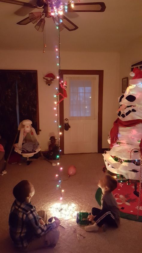 elf on the shelf caught stringing lights in the living room, hanging from them Lights In The Living Room, Elf Ideas Easy, Elf Funny, Houses Christmas, Elf Magic, Awesome Elf On The Shelf Ideas, Xmas Elf, Elf Activities, Elf Antics