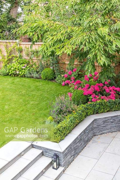 Steps and retaining wall between levels Garden Steps On A Slope Retaining Walls, Step Down Retaining Wall, Patio With Retaining Wall And Steps, Retaining Wall With Steps, Stepped Garden, Slope Garden Ideas, Patio Retaining Wall Ideas, Modern Retaining Wall Ideas, Split Level Garden Ideas