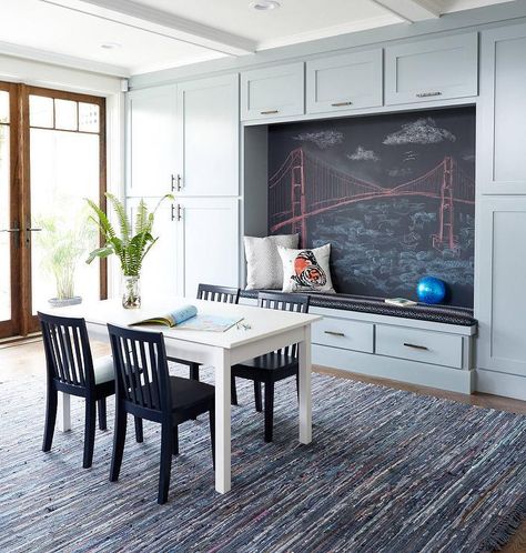 Gray contemporary homework and playroom features a wall lined with gray built in cabinets accented with bronze pulls and positioned framing a built-in gray bench topped with a black cushion fixed against a large chalkboard. Cabinets Playroom, Built In Reading Nook, Homework Station Ideas, Storage Playroom, Den Library, Homework Room, Homework Station, Library Office, Playroom Storage