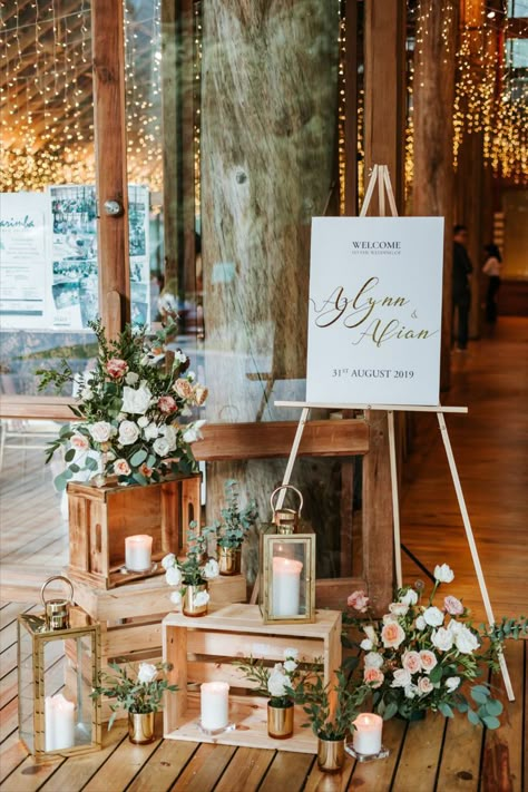 A wedding clad in gold. This wedding theme surely gives off a more warm and rustic feel. Decorated with fresh flower arrangements of white and pink roses at the entrance, tables and wedding arch. Plus, a viking table seating set up with pillar candles, foliage lining and cutleries on the table, with gold chiavari chairs. Welcome Table Wedding Entrance, Welcome Table Wedding, Wedding Entrance Table, Wedding Welcome Table, Reception Entrance, Wedding Entrance Decor, Welcome Table, Wedding Entrance, Table Wedding