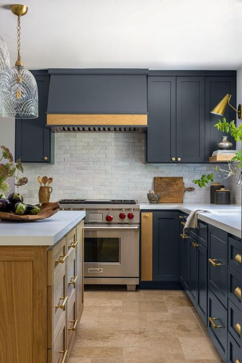 This gourmet kitchen features deep navy blue cabinets and a range hood. The rich color contrasts beautifully with the light gray stone backsplash and white stone countertops. Backsplash With Blue Cabinets, White Stone Countertops, Kitchen Cabinets Backsplash, Modern Colonial Kitchen, Light Grey Backsplash, Navy Blue Cabinets, Kitchens Backsplash, Navy Kitchen Cabinets, Blue Gray Kitchen Cabinets