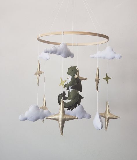 Baby mobile with dragon is perfect decoration for a baby girl or boy nursery room. This mobile its a one of a kind final touch to your new little one.Simply,delicate decoration for nursery. Mobile includes  6 gold stars  6 white clouds Green dragon  Diameter of the hoop 10 inches Crib arm attachment  is not included! Fairy Forest Nursery Theme, Elven Themed Nursery, Dragon Mobile Baby, Cottagecore Nursery Fairy, Dnd Nursery Theme, Fairy Tale Nursery Theme, Dragon Baby Nursery, Dragon Themed Nursery, Magical Forest Nursery