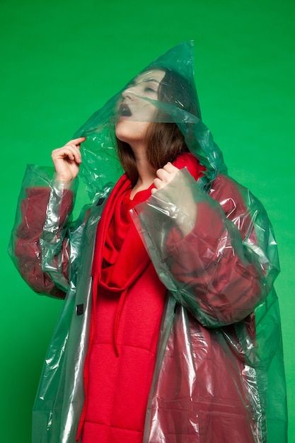 Premium Photo | Calm female wearing transparent plastic raincoat and red clothes standing on green background in studio Transparent Raincoat, Transparent Clothing, Red Raincoat, Red Clothes, Rainwear Fashion, Plastic Raincoat, Pvc Raincoat, Clothes Stand, Studio Green