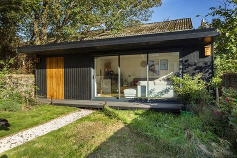 This contemporary Garden Room design has provided valuable extra space for a family in Sussex. It contains side storage which is finished in cedar - a beautiful contrast to the black timber cladding on the rest of the building. As well as clever side storage, this multi-functional building also has a shower room. Check out the following features:

- 8m x 4m Garden Room
- Side Storage with Cedar Entrance
- Stainted Black Timber Cladding 
- uPVC Double-Glazed Sliding Doors
- Ensuite with Toilet Black Timber Cladding, Room With Toilet, Garden Room Design, Contemporary Garden Rooms, Backyard Guest Houses, Shower Storage, Roller Doors, Black Garden, Timber Cladding