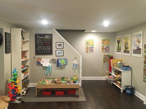 Basement Playroom decor reading area train table and puzzles Rectangle Basement Layout Ideas, Finished Basement Playroom, Unfinished Basement Playroom, Basement Play Area, Narrow Basement Ideas, Home Daycare Ideas, Open Basement, Low Ceiling Basement, Daycare Rooms