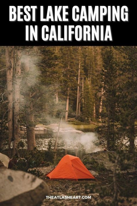 A wooded lakeside campsite with a small orange tent and smoke rising from a campfire, with the text overlay, "Best Lake Camping in California." Fort Bragg California Camping, Silverwood Lake California, Lake Isabella California, Camping In Southern California, Northern California Camping, California Lakes, Bass Lake California, June Lake California, Camp Hacks