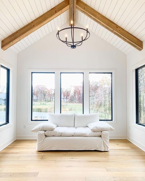 Vaulted Ceiling With Chandelier, Wood Pitched Ceiling, Vaulted Ceiling Square Windows, Planked Ceiling With Beams, Black Picture Window, Vaulted Shiplap Ceiling, White Vaulted Ceiling, Shiplap Ceiling With Beams, Vaulted Ceiling With Wood Beams