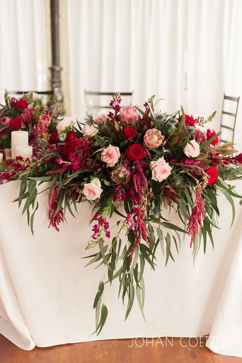 Lush burgundy arrangement including Pink Ice Protea, Red Roses, Burgundy Snapdragons, Amaranthus and Sea Holley Red And Burgundy Flower Arrangements, Protea And Red Rose Bouquet, Pink And Burgundy Flower Arrangements, Red Pink Flower Arrangements, Red Roses Flower Arrangement, Pink And Red Flower Arrangements, Red And Pink Flower Arrangements, Pink And Red Wedding Flowers, Red Wedding Flower Arrangements