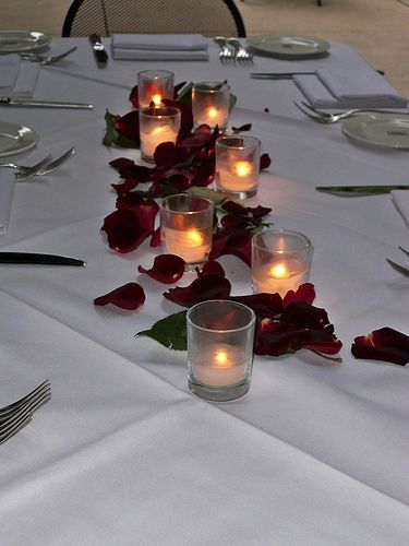 simple candle centerpiece with petals Candle And Petals Centerpiece, Rose Petals And Candles Centerpiece, Simple Red Rose Centerpiece, Rose Petal Table Decor, Rose Petals On Table, Rose Petals Wedding Table, Rose Petals Table Decor, 15 Decorations, Votive Centerpieces