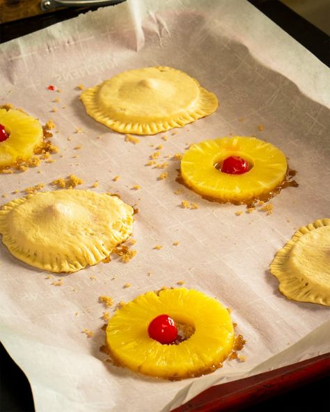 Wax paper lined tray topped with cherries inside pineapple rings before baking. Some cherry filled pineapple rings have been wrapped in pastry dough before baking. Pineapple Turnovers Recipe, Pineapple Puffs, Upside Down Pastry, Upside Down Desserts, Pineapple Cookies, Turnover Recipes, Puff Pastry Desserts, Cookie Cake Pie, Pineapple Rings