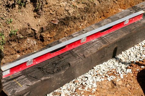 Picture of Level the first tie in the wall Railroad Tie Driveway Edging, Railroad Ties Landscaping, Railroad Tie Retaining Wall, Diy Retaining Wall, Railroad Tie, Driveway Edging, Backyard Retaining Walls, Rock Retaining Wall, Building A Retaining Wall