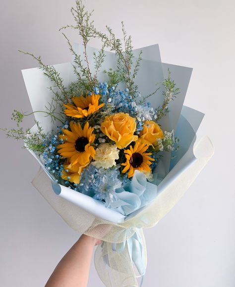 Sunny skies is the vibe. A fun mix of sunflowers, yellows, blues, whites and touches of greenery. Images shown are examples and can differ depending on the supply and season. Blue Flowers And Sunflowers, Sunflower Blue Bouquet, Sky Blue Flower Bouquet, Light Blue And Yellow Bouquet, Mixed Flower Arrangements, Blue And Yellow Flower Arrangements, Arrangements With Sunflowers, Sunflower Bouquet Aesthetic, Yellow And Blue Bouquet